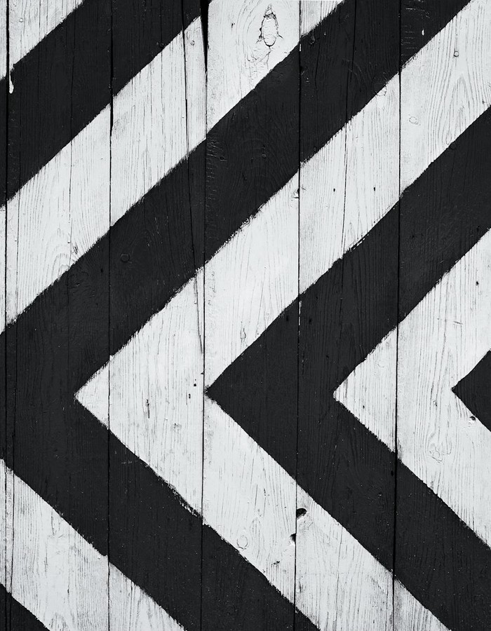 Black and white geometric pattern on wooden planks, ideal for modern design backgrounds.