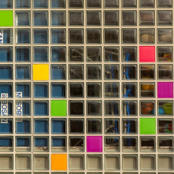 Colorful glass brick wall with a geometric pattern featuring various bright shades and abstract design elements.